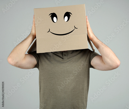 Man with cardboard box on his head on grey background