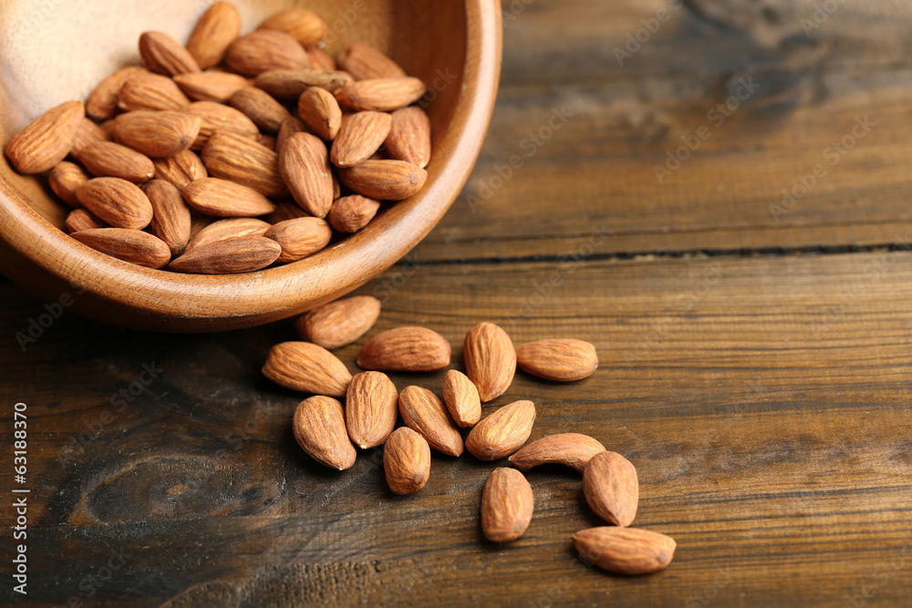 Almonds in bowl on color wooden background Almonds in bowl on color wooden background