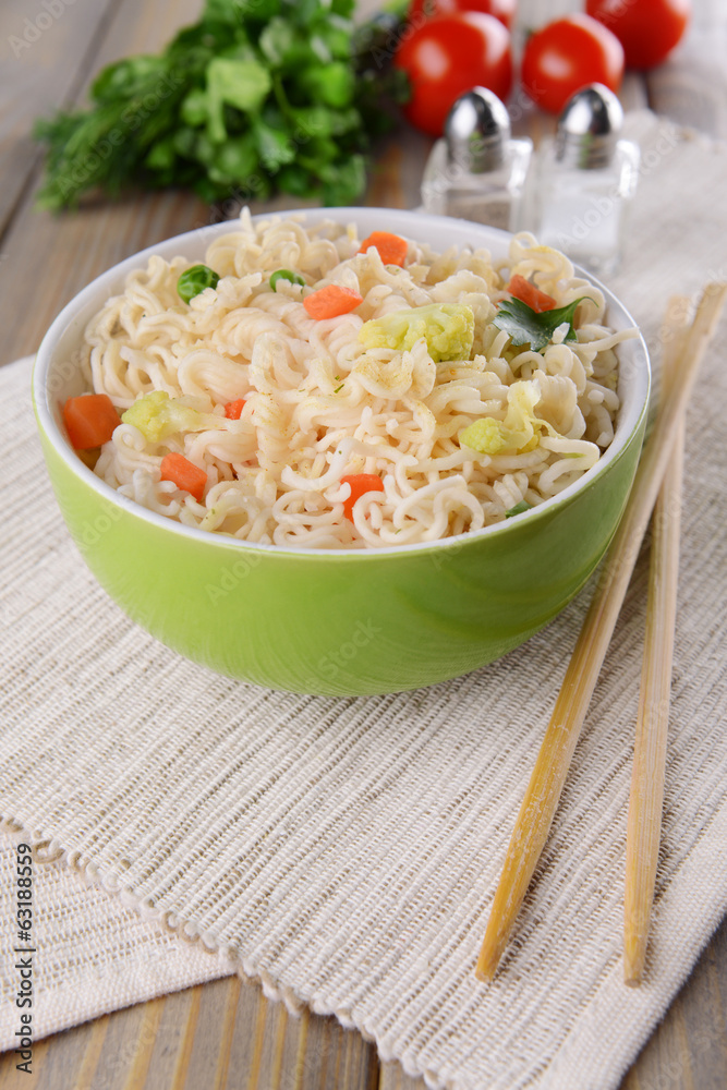Tasty instant noodles with vegetables in bowl on table close-up Tasty instant noodles with vegetables in bowl on table close-up