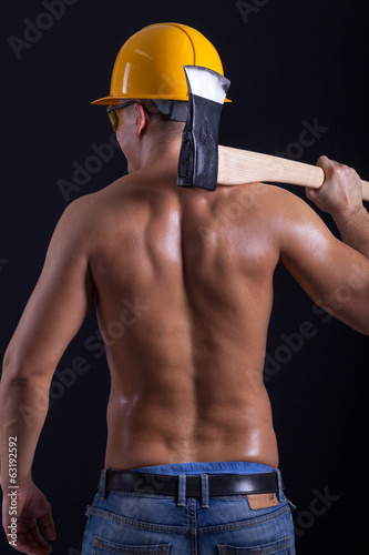 muscular man holding hatchet on black background