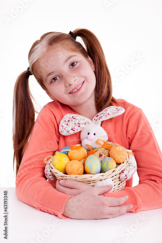 young smiling freckles girl holding a basket of Easter eggs