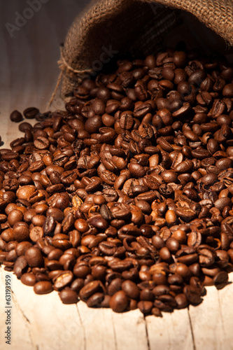  Coffee beans in burlap sack against dark wood