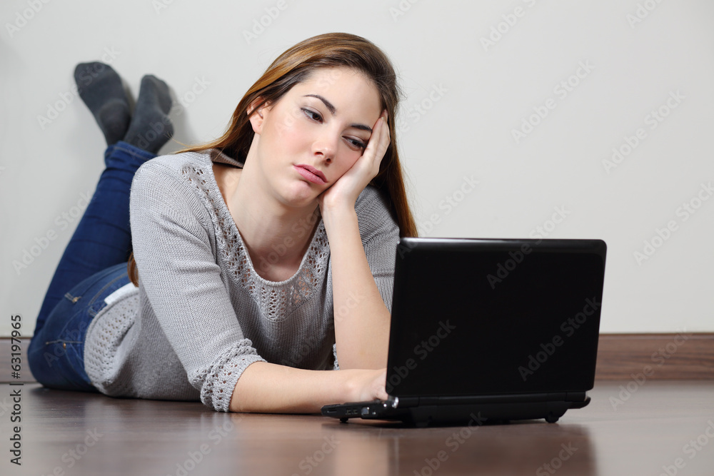 Bored teenager girl browsing social media in a laptop Bored teenager girl browsing social media in a laptop