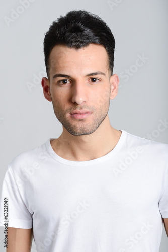 Serious young man standing against white background © javiindy