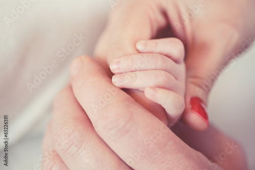 Quadro em tela Hand a newborn in the hands of parents