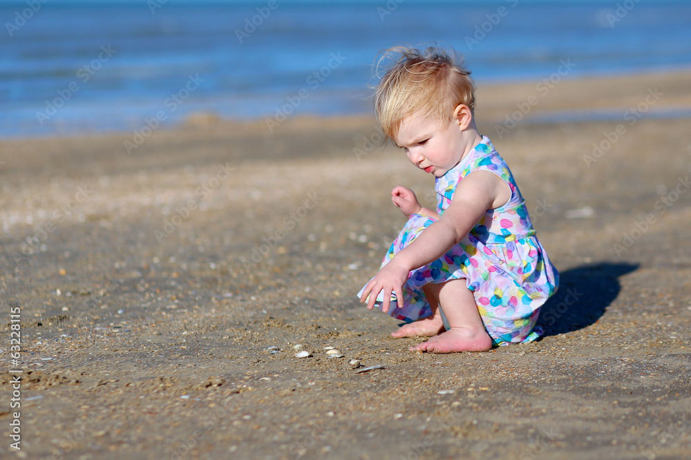 Cute toddler girl playing on the beach on summer day Cute toddler girl playing on the beach on summer day