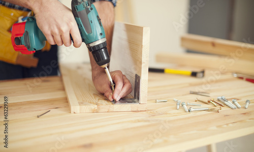 Close up of carpenter working with drill