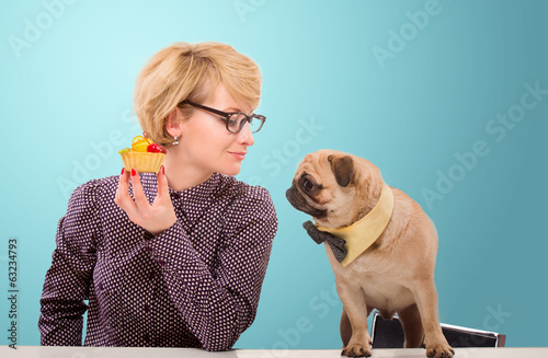 Pretty woman stopping her dog from eating cake