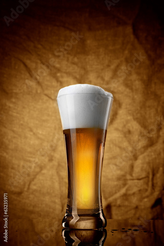 Beer in glass on brown background