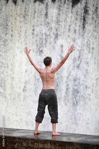 man with raised arms at the waterfall