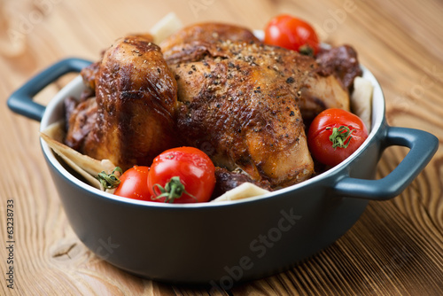 Close-up of whole baked spicy chickling with mini tomatoes