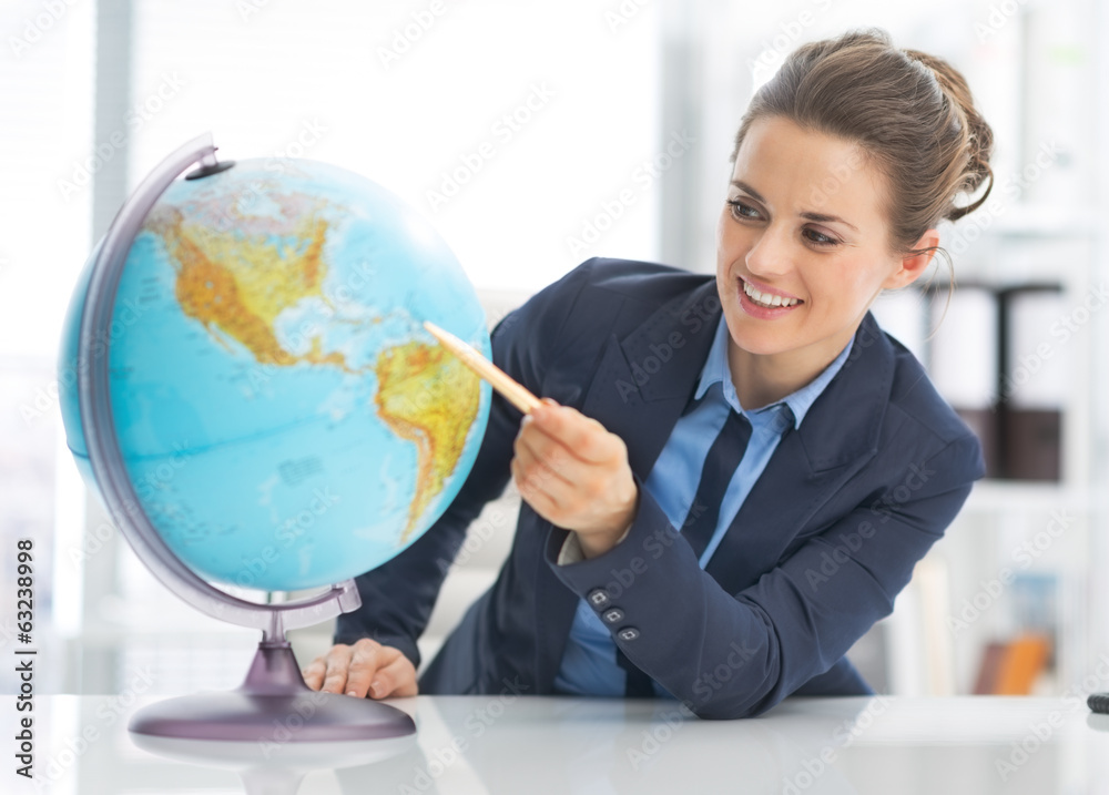 Portrait of happy business woman pointing on earth globe Portrait of happy business woman pointing on earth globe