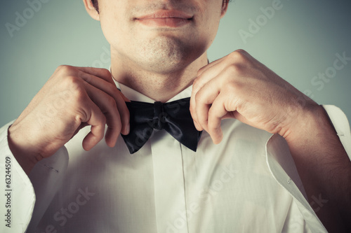 Happy young man tying abow tie