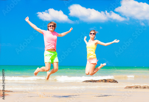 front view of young couple in bright clothes jumping on the