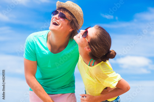 Closeup of happy young couple in sunglasses on beach smiling and