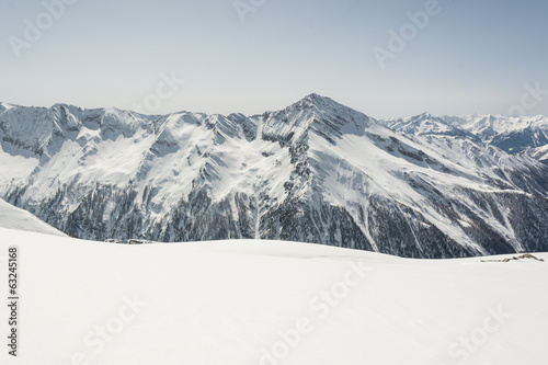 Snow covered slope with mountain ridge in the back photo