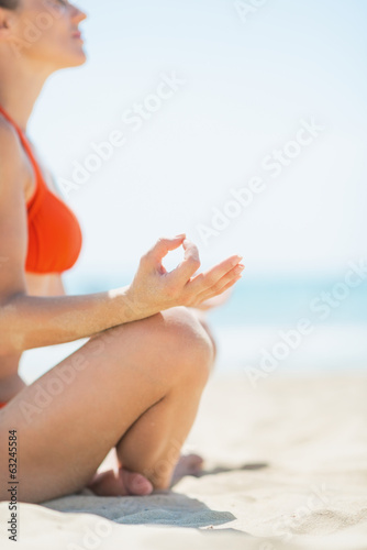 Closeup on young woman doing yoga on beach