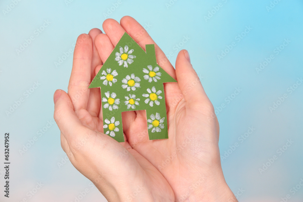 Little paper house in hand close-up, on light background Little paper house in hand close-up, on light background