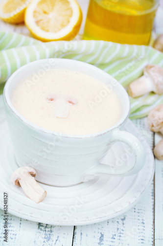Delicate mushroom sauce in cup on wooden table close-up