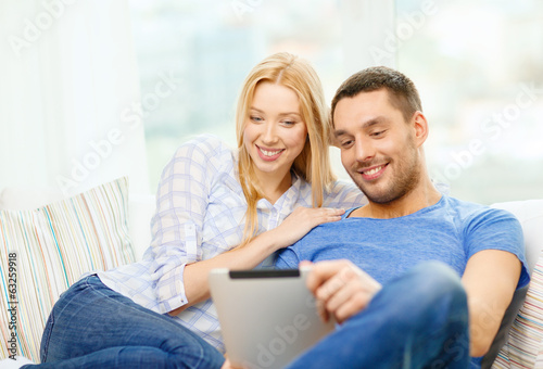 smiling happy couple with tablet pc at home