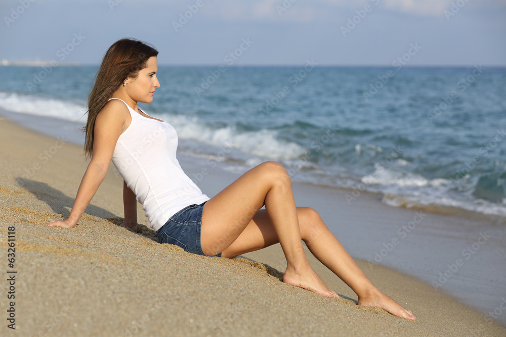 Beautiful woman sitting on the sand of the beach