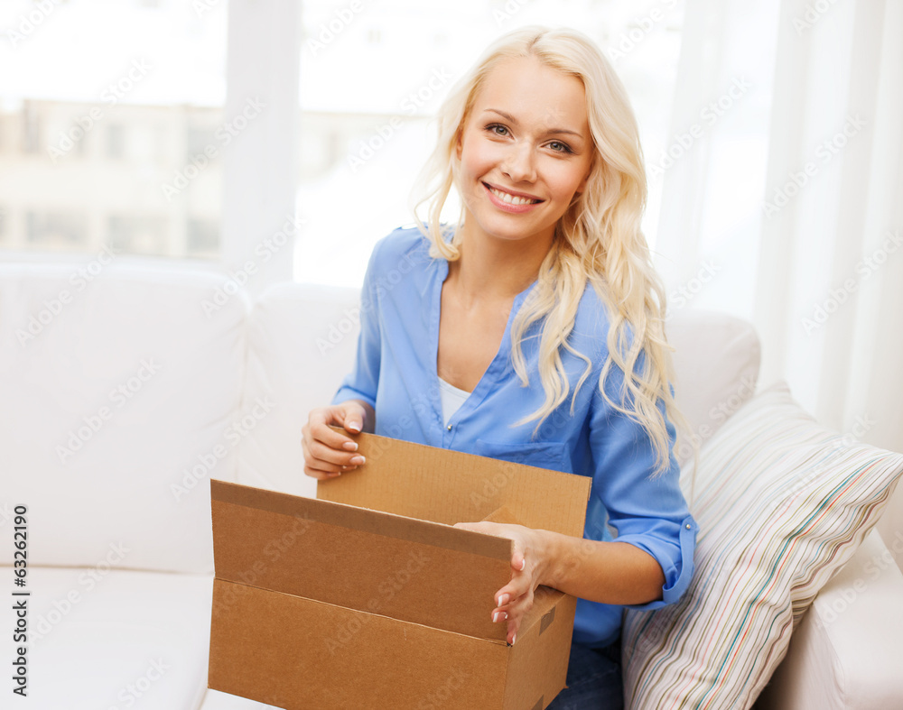 smiling young woman opening cardboard box at home smiling young woman opening cardboard box at home
