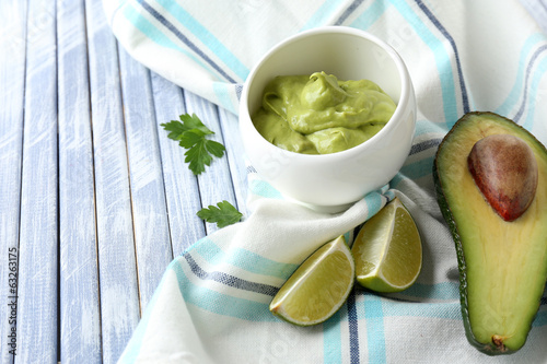 Fresh guacamole in bowl on wooden table