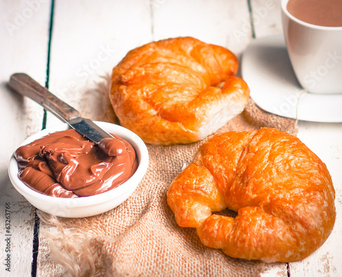 Fresh baked croissants with chocolate cream and hot cocoa on woo