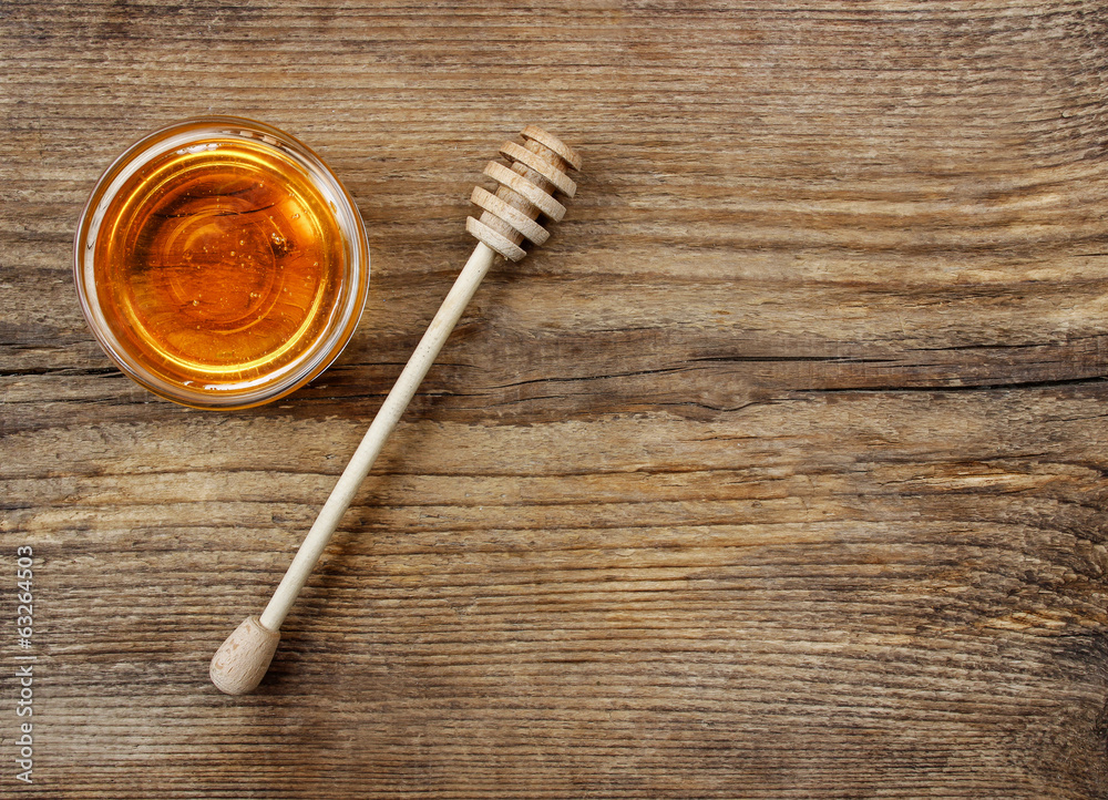 Fototapeta premium Bowl of honey on wooden table. Symbol of healthy living