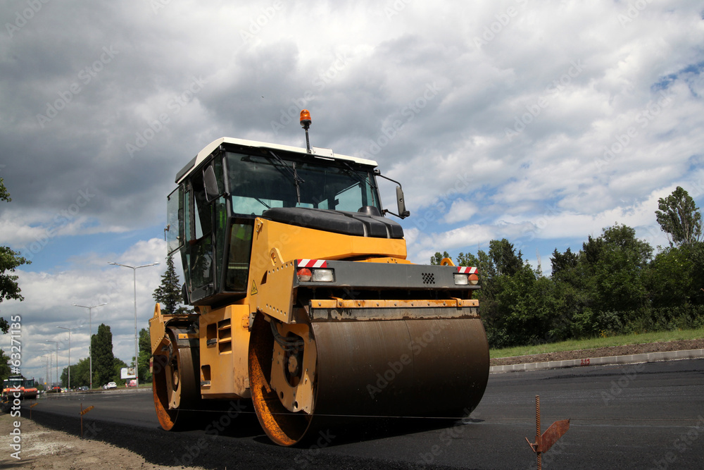 Large road-roller paving a road. Road construction Large road-roller paving a road. Road construction