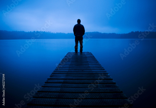 Man Standing on a Jetty by Tranquil Lake photo