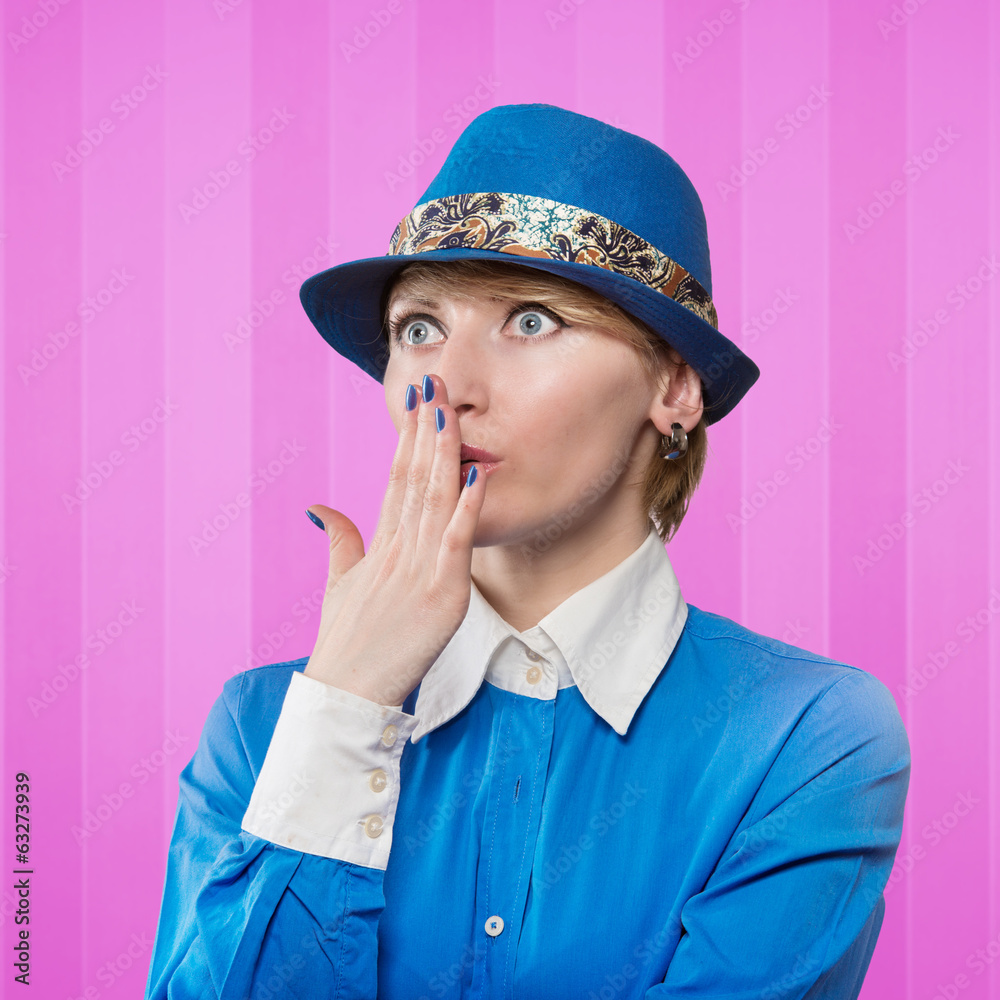Woman in a blue hat covering the mouth with her hand Woman in a blue hat covering the mouth with her hand