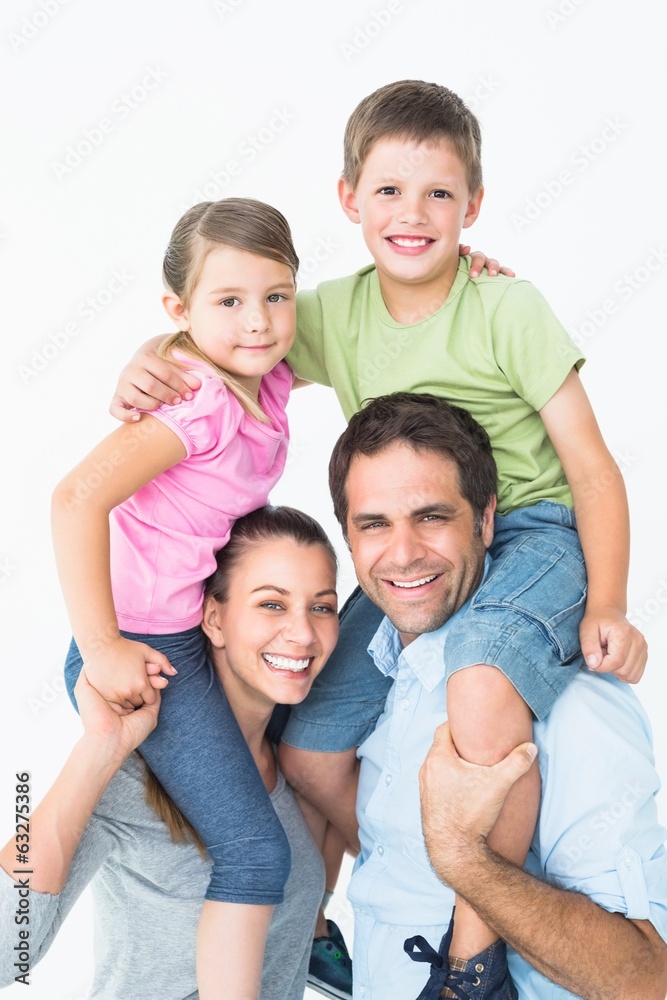 Parents giving their children piggyback ride smiling at camera Parents giving their children piggyback ride smiling at camera