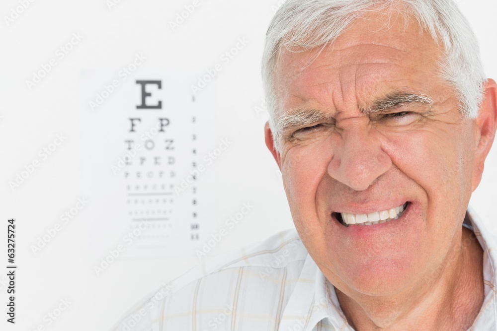 Portrait of a senior man with eye chart in background