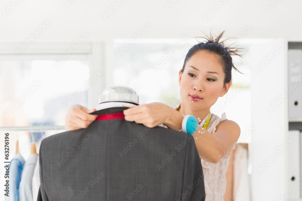 Concentrated fashion designer measuring suit on dummy Concentrated fashion designer measuring suit on dummy