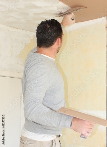 A plasterer plastering a ceiling