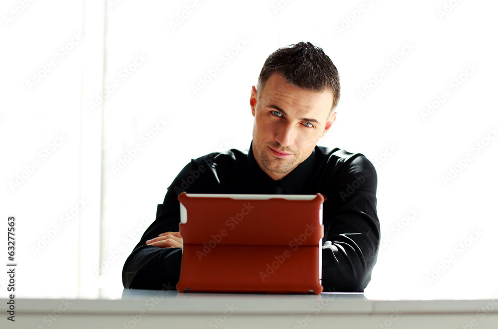 Confident businessman sitting at the table with tablet computer Confident businessman sitting at the table with tablet computer