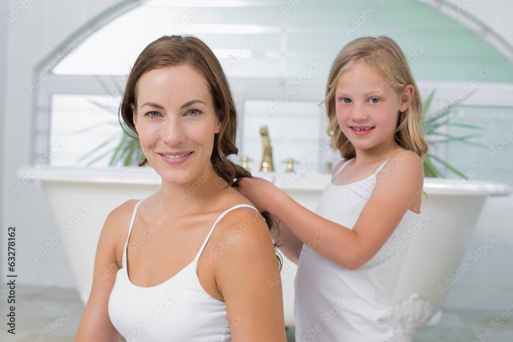 Cute little girl braiding mother's hair in bathroom Cute little girl braiding mother's hair in bathroom