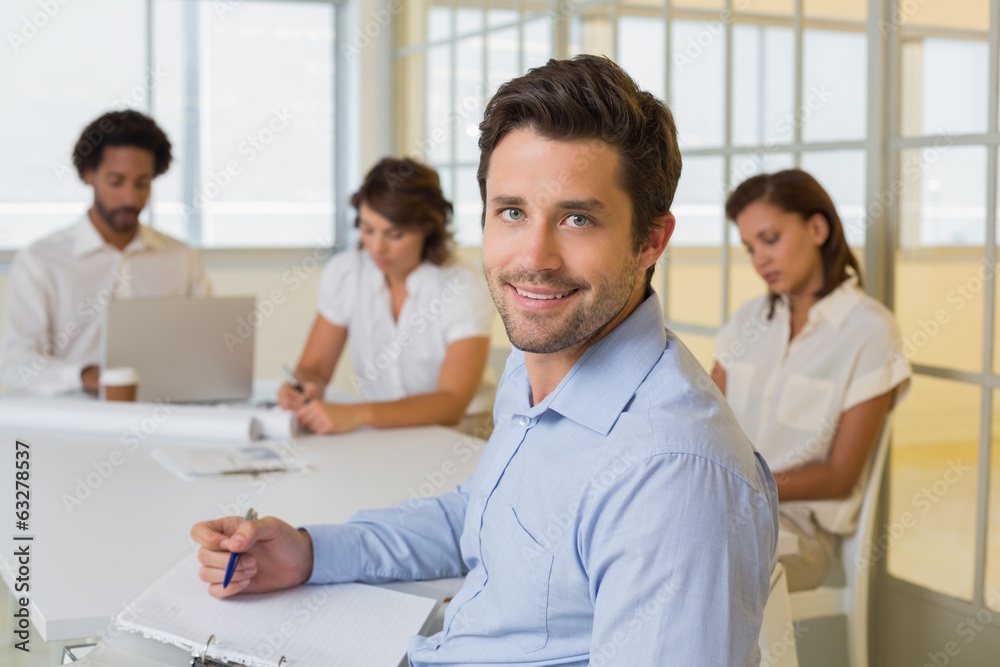 Smiling businessman with colleagues in meeting in at office Smiling businessman with colleagues in meeting in at office