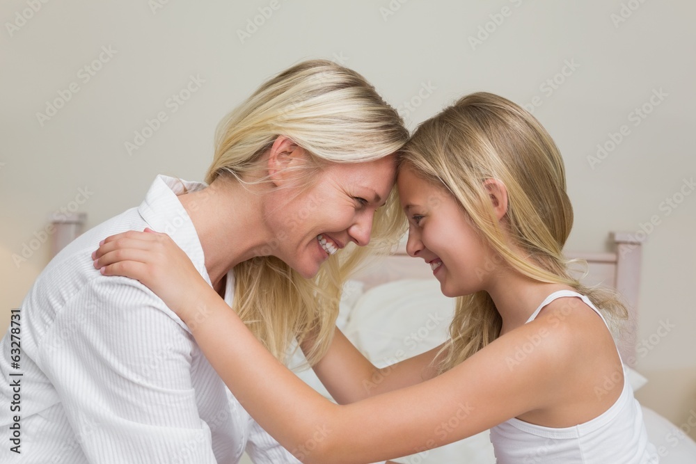Mother and daughter with head to head in bedroom