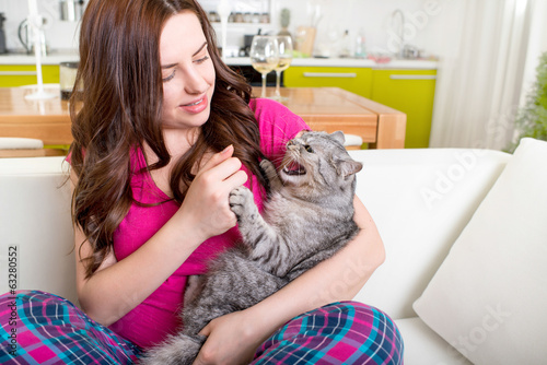 Angry cat bites with claws woman at home