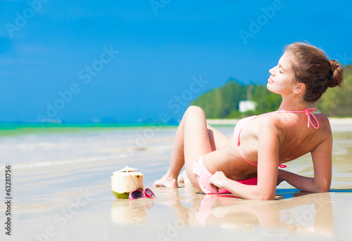 Happy young woman on the beach with coconut cocktail and