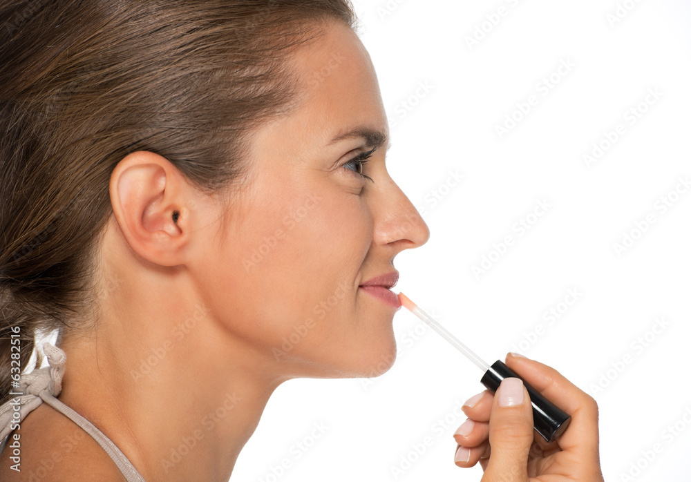 Profile portrait of young woman applying lip gloss Profile portrait of young woman applying lip gloss