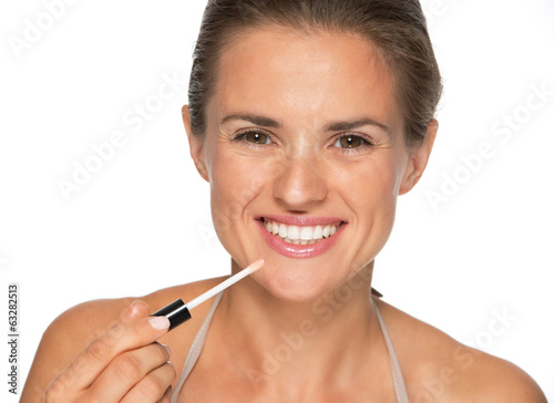 Happy young woman applying lip gloss