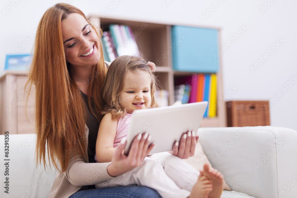 Mother with little daughter enjoying the free net at home Mother with little daughter enjoying the free net at home