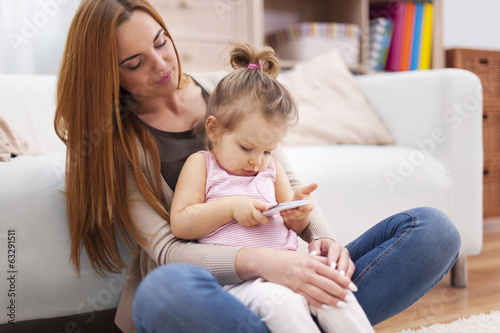 Mother and baby with mobile phone at home .