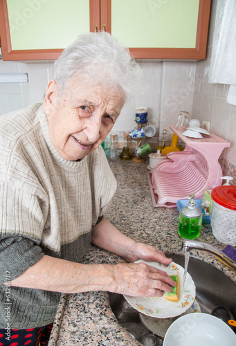 senior woman washing dishes in the sink under water