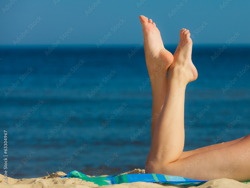 Summer vacation. Legs of sunbathing girl on beach Summer vacation. Legs of sunbathing girl on beach