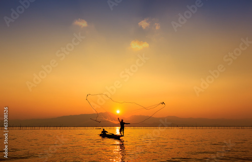 throwing fishing net during sunset , thai