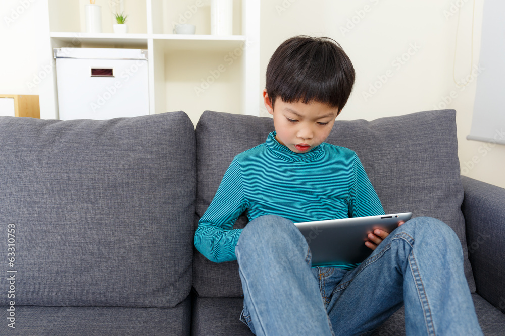 Asian little boy watching on tablet and sitting on sofa Asian little boy watching on tablet and sitting on sofa